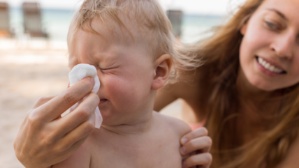Baby blowing nose with mom help. Nurturing Little Blossoms: Dr. Reyna's Guide to Safely Navigating Allergy Season with Your Baby